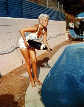 L'actrice américaine Jayne Mansfield avec une bouteille de champagne, près d'une piscine