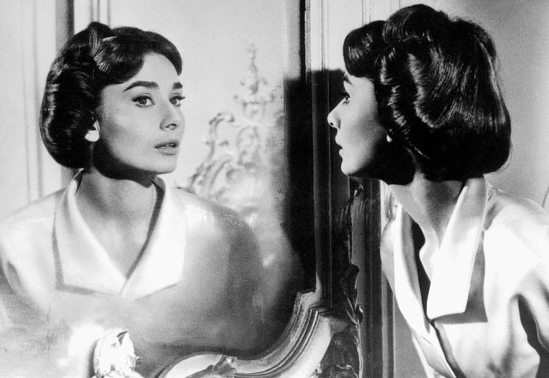Actress Audrey Hepburn looking at her reflection in the mirror à 