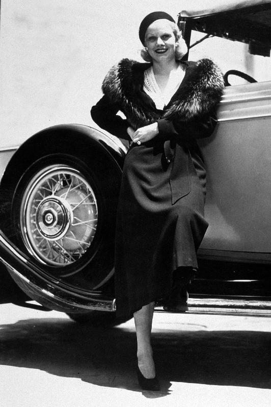 American Actress Jean Harlow posing near a car à 